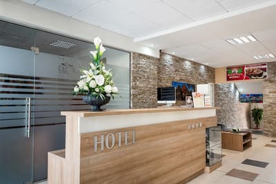 Recepciópult világos fa fronttal, mögötte kőburkolat és üvegfal