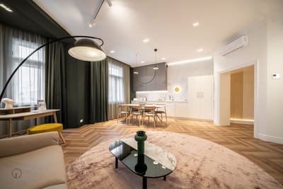 Apartman nappalija zöld függönyökkel és ívlámpával, mögötte az étkező