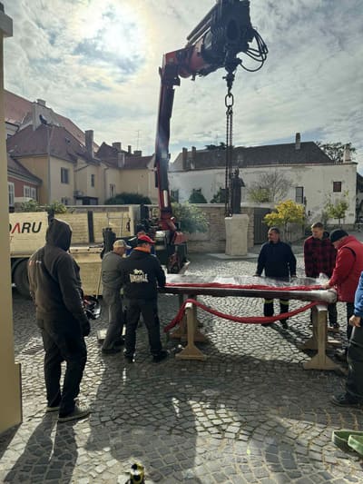 A becsomagolt kapuszárny hevederben a daru horgán, több emberrel körülötte